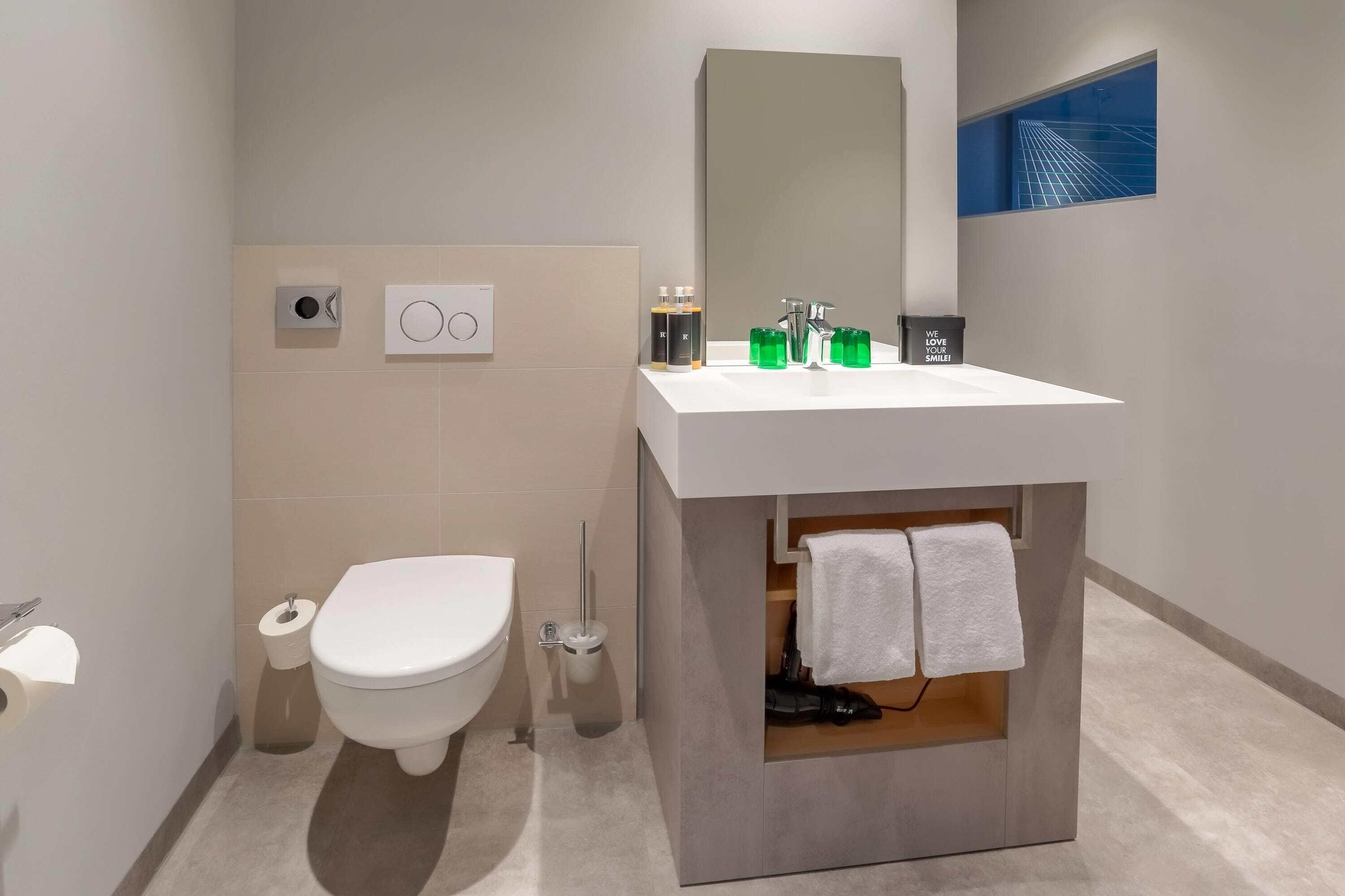 Un bagno moderno con il water, un bidet e un mobile lavabo con specchio e lavandino.