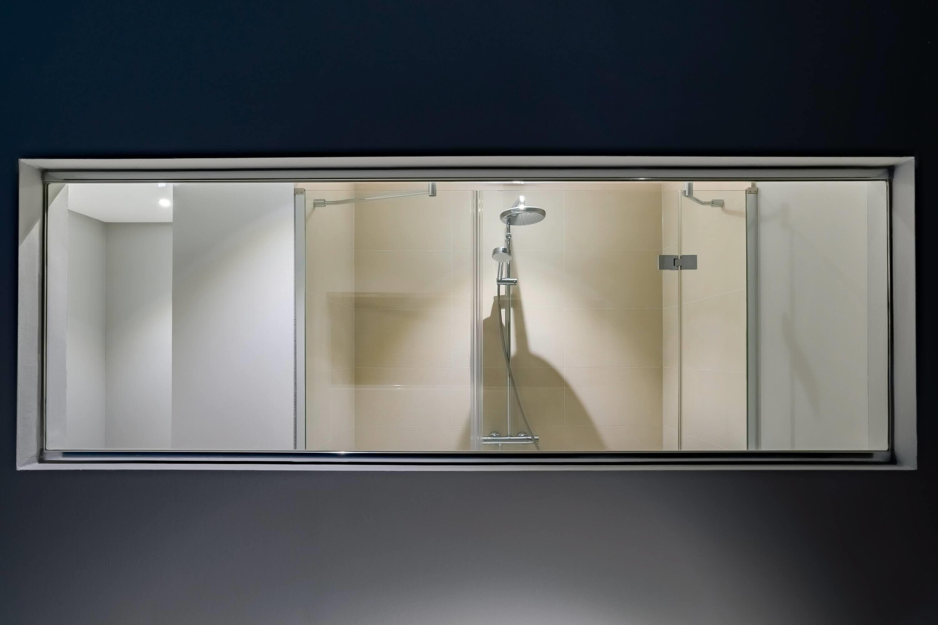 Une salle de bain dotée d’une douche à parois de verre, d’un pommeau de douche à main et d’un robinet mural.