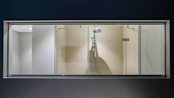 Une salle de bain dotée d’une douche à parois de verre, d’un pommeau de douche à main et d’un robinet mural.