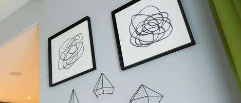 Una parete con tre opere d'arte incorniciate e due sculture geometriche.