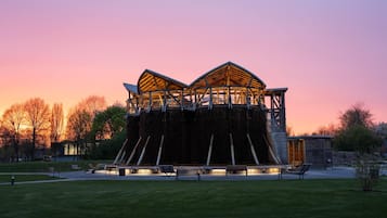 A modern building with a unique roof structure, surrounded by a grassy area and trees.