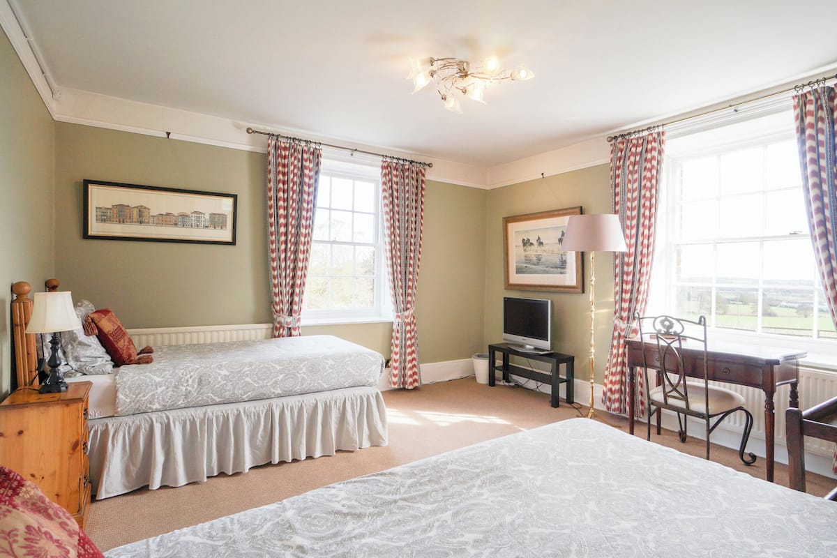 A bedroom with two beds, a television, a desk, and a chair.