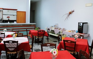 A restaurant with multiple tables covered in red tablecloths, wooden chairs, and flower centerpieces. - il Chiostro delle Cererie (Matera)