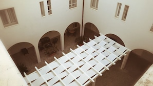 A courtyard with white walls, multiple arches, and several windows. - il Chiostro delle Cererie (Matera)
