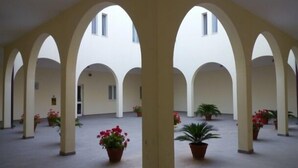 A spacious courtyard with arches, potted plants, and a tiled floor. - il Chiostro delle Cererie (Matera)