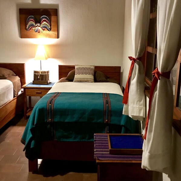 A hotel room with a bed, a nightstand, a lamp, and a wall-mounted artwork.