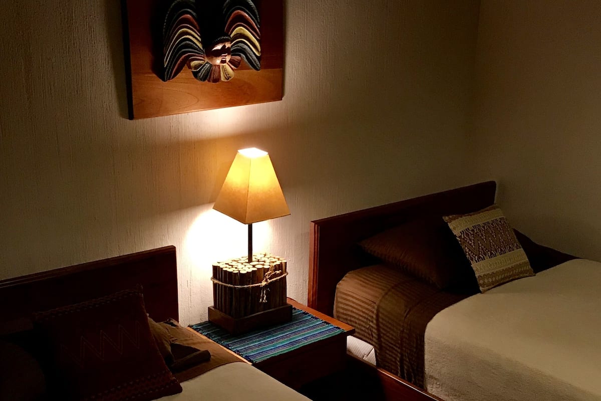 Ein Hotelzimmer mit zwei Betten, einem Nachttisch mit Lampe und einem Wandbild über den Betten.