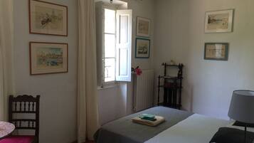 Un dormitorio con dos camas, una silla, una mesa y varias fotografías enmarcadas en las paredes.