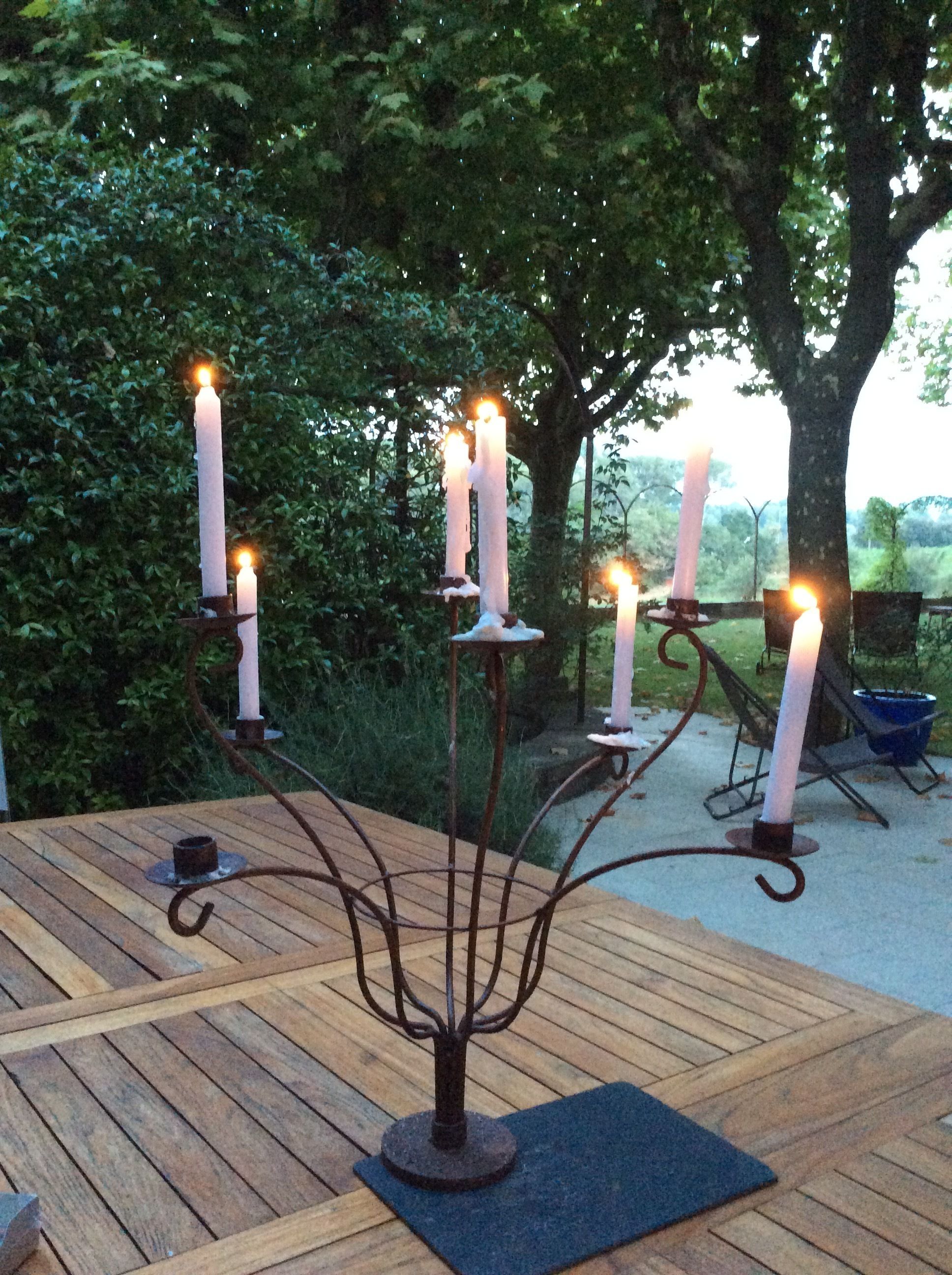 A wooden table with a metal candle holder in the center, surrounded by greenery.