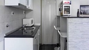 A modern kitchen with white cabinets, a black countertop, and a microwave. - Royal Apartments (Belgrade)