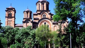 A large, historic building with multiple domes and arched windows, surrounded by lush greenery. - Royal Apartments (Belgrade)