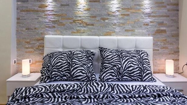 A bed with zebra-patterned bedding, a white headboard, and two bedside lamps. - Royal Apartments (Belgrade)