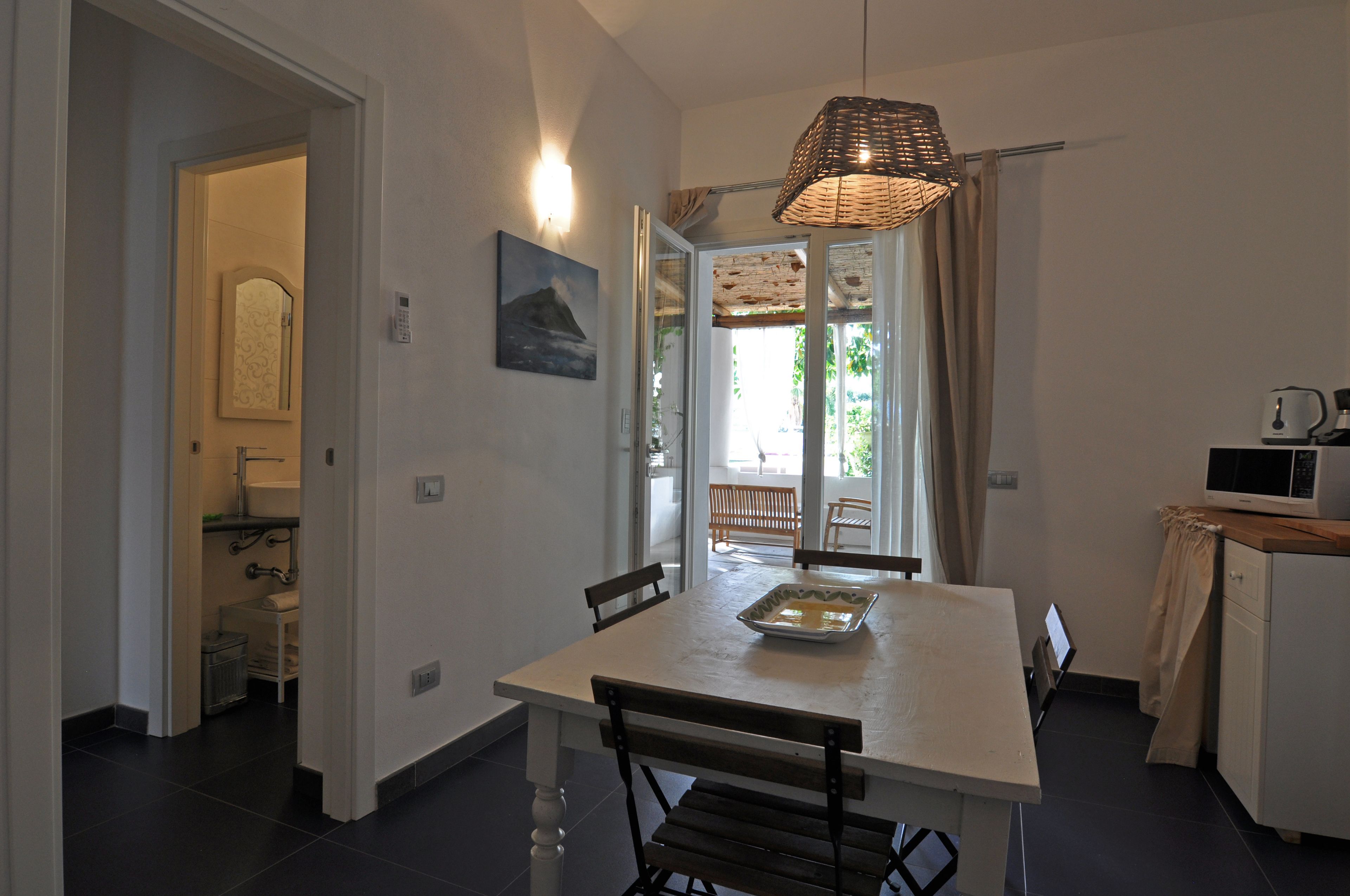 Un espace repas comprenant une table, des chaises, un luminaire suspendu et une vue sur l’extérieur.