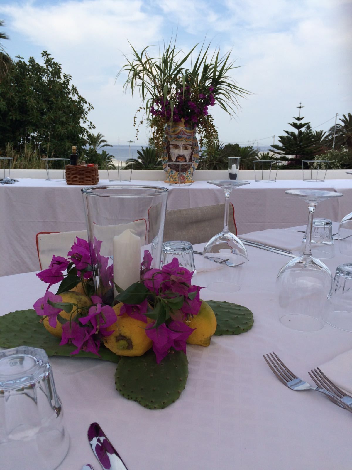 A table set for a meal with a vase of flowers, a candle, and a bottle of wine.