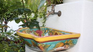 A decorative ceramic sink with floral patterns, mounted on a white wall.
