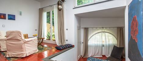 A room with a bed, a chair, a small table, and a window.