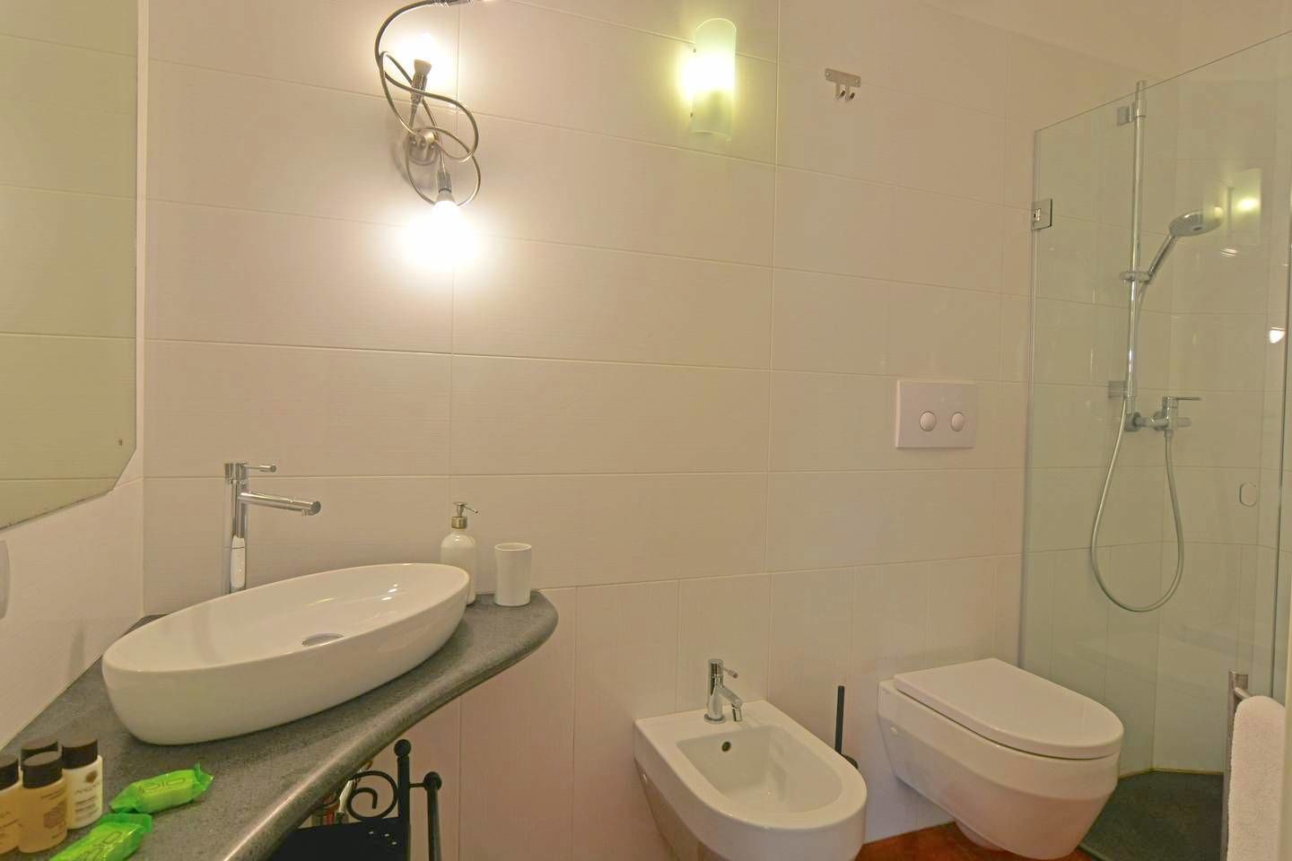 A bathroom with a large sink, bidet, toilet, and glass shower enclosure.