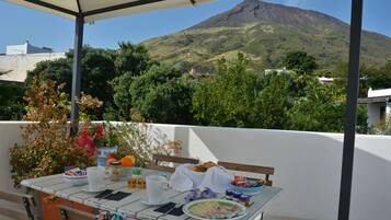 A table set outdoors with food and drinks, overlooking a mountain.