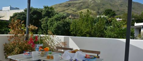 A table set outdoors with food and drinks, overlooking a mountain.