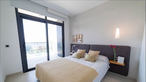 A modern bedroom with a large bed, a nightstand, a wall-mounted light, and a view through a sliding door. - Sunset Drive Mar Holidays (Benidorm)