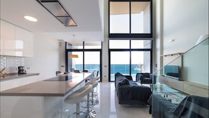 A modern kitchen with a central island, bar stools, and a large window overlooking the sea. - Sunset Drive Mar Holidays (Benidorm)