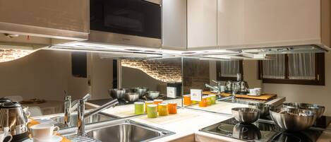 A modern kitchen with stainless steel appliances, a double sink, and various cooking utensils.