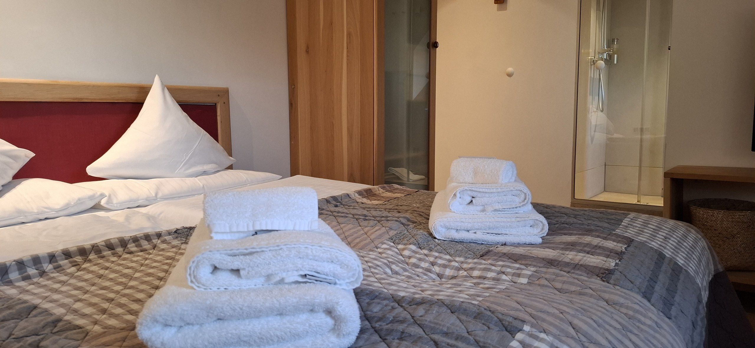 Una camera d'albergo con un letto, una doccia e un letto rifatto con asciugamani.