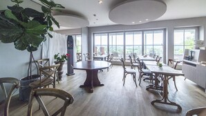 A spacious dining area with high ceilings, large windows, and several dining tables and chairs. - Die Aussicht (Neuburg)