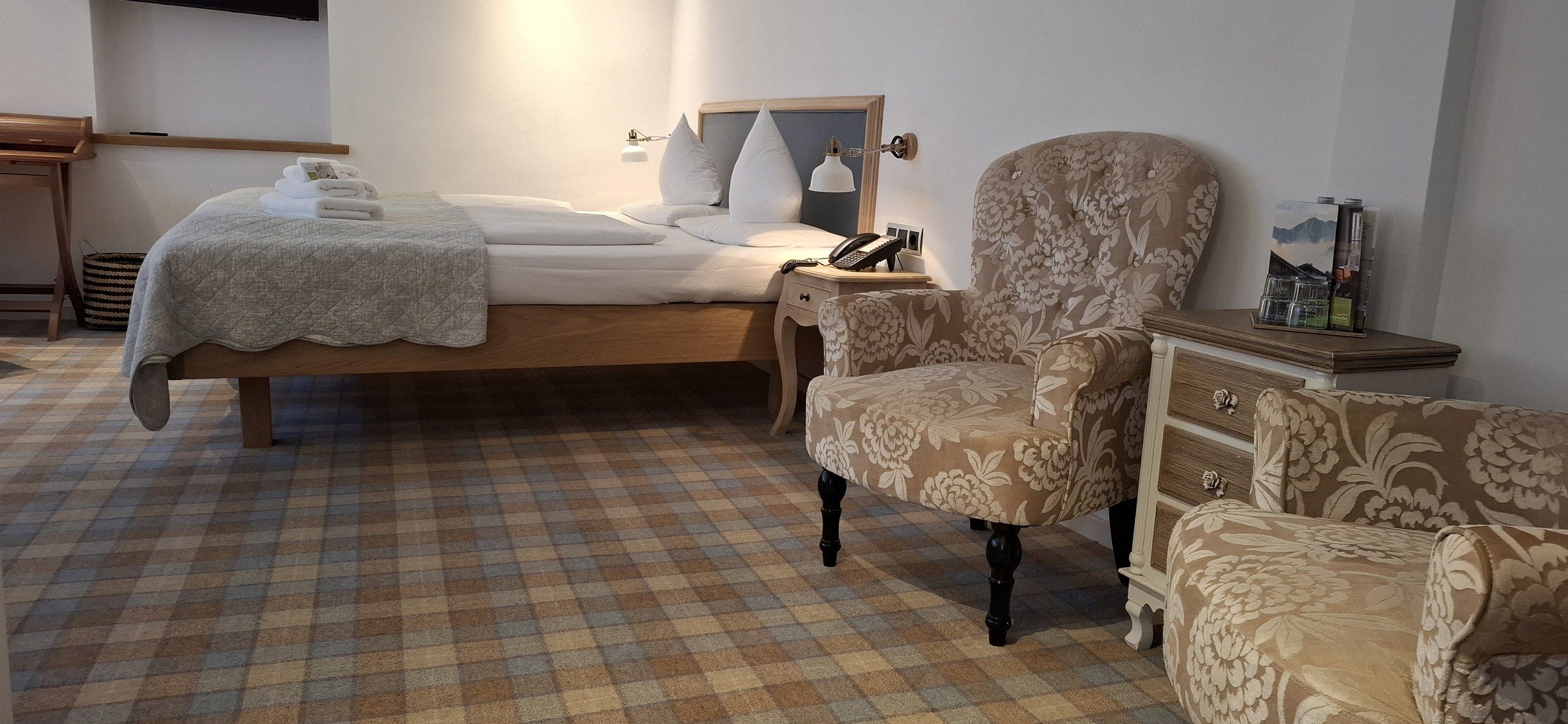 A bedroom with a bed, a chair, a nightstand, and a dresser.