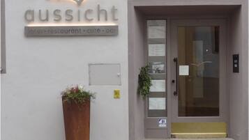 A hotel entrance with a sign reading "aussicht hotel: restaurant: cafe: bar".
