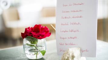 A handwritten note with a red rose in a glass vase on a table.