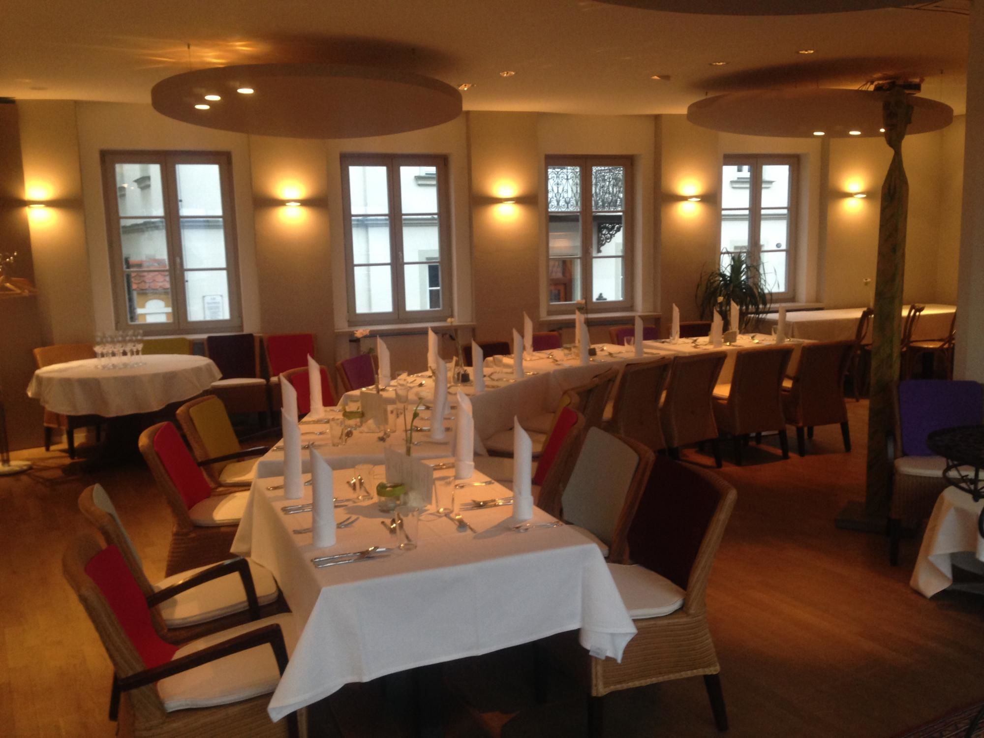 Ein Restaurant mit runden Tischen, gedeckt für ein Essen, mit weißen Tischdecken und Kerzen.