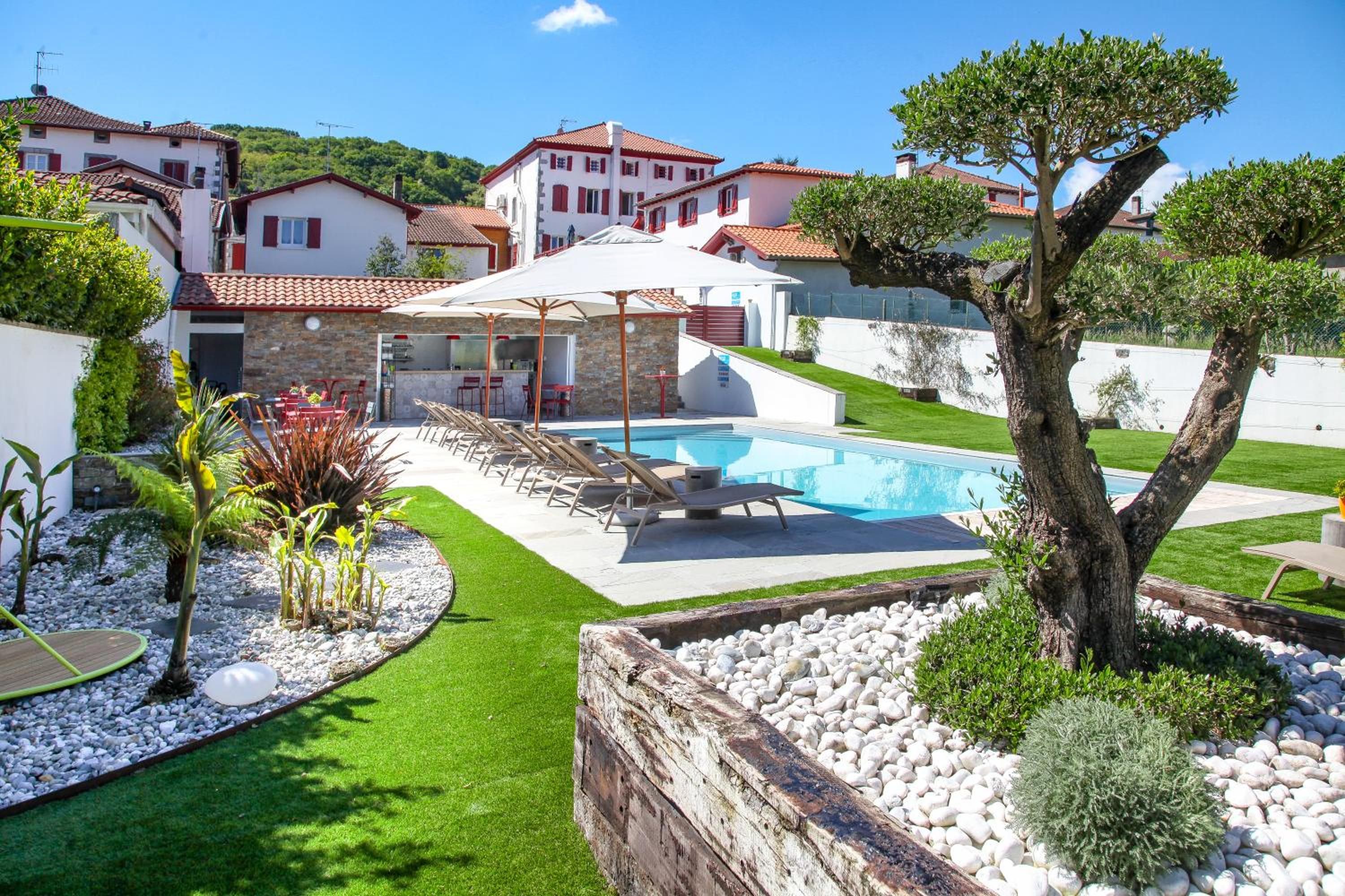 Ein Pool mit Liegestühlen, ein Grillbereich und ein gepflegter Garten mit Baum und Sträuchern.