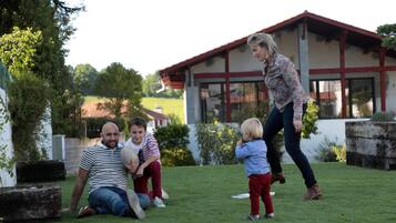 Una familia en un espacio abierto con césped y una casa al fondo.