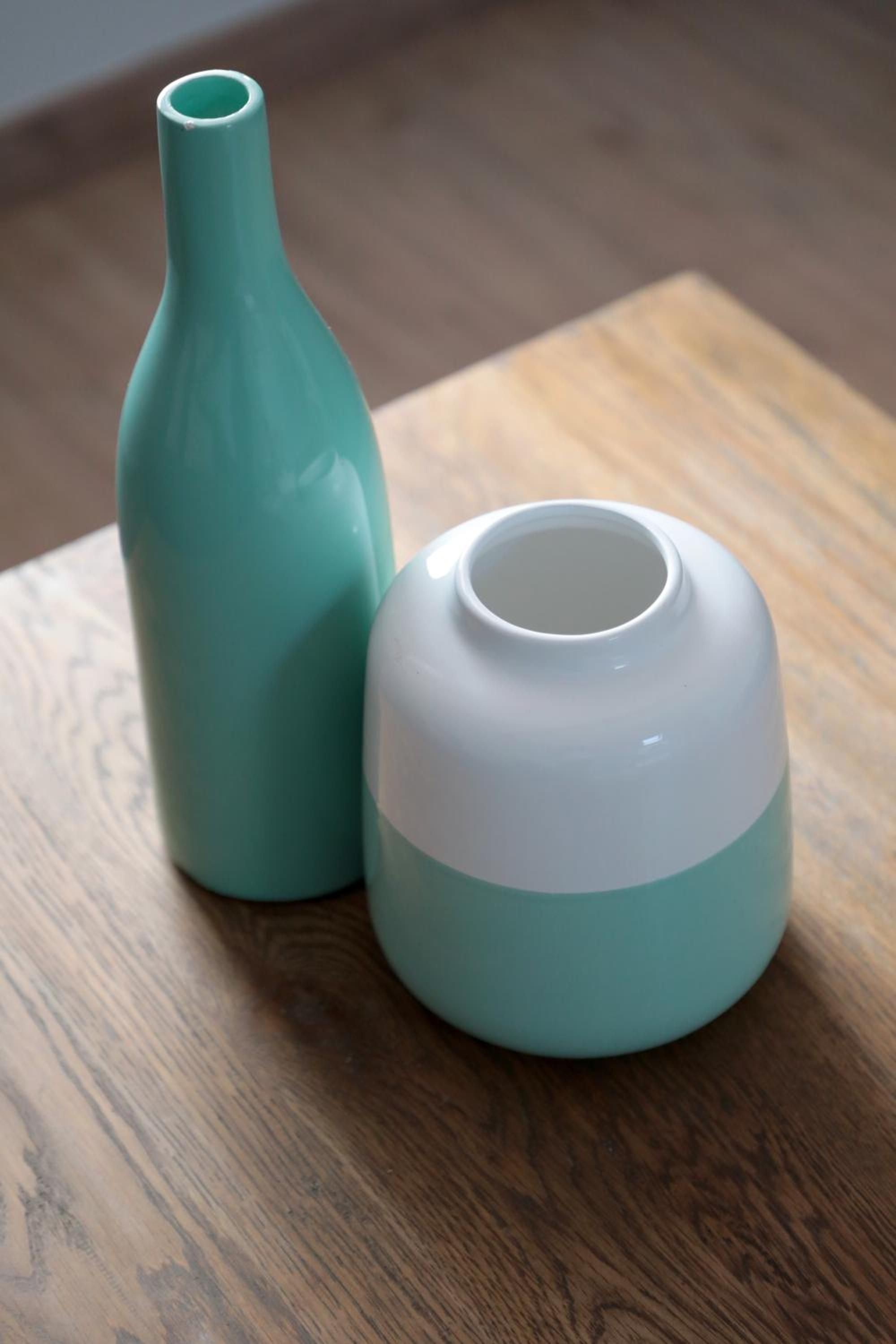Deux vases en céramique sur une surface en bois.