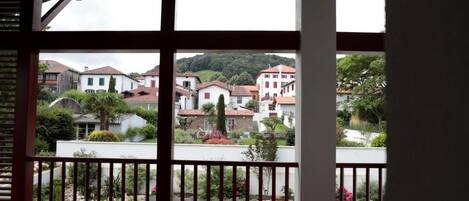 A balcony with a view of a residential area, a wooden floor, and a white railing.