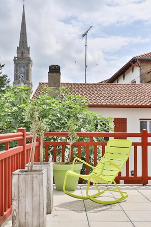 A balcony with a red railing, a yellow rocking chair, and a potted plant. - Hôtel Argia (Hasparren)