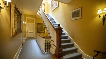 A staircase with a wooden handrail and a carpeted floor, leading to a door at the top.