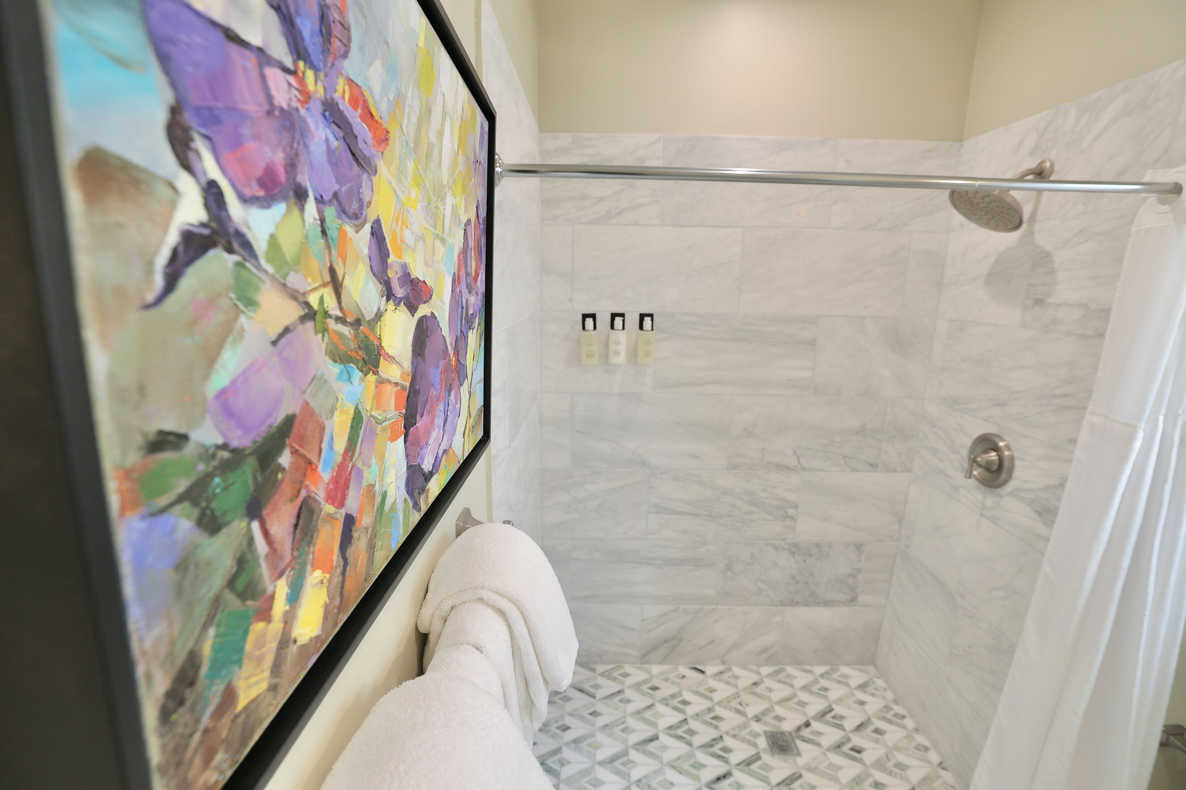 A shower with a glass door, a tiled floor, and a showerhead.