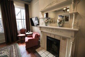A room with a fireplace, a television, and two chairs.