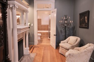 A hallway with a fireplace, a chandelier, and a chair.