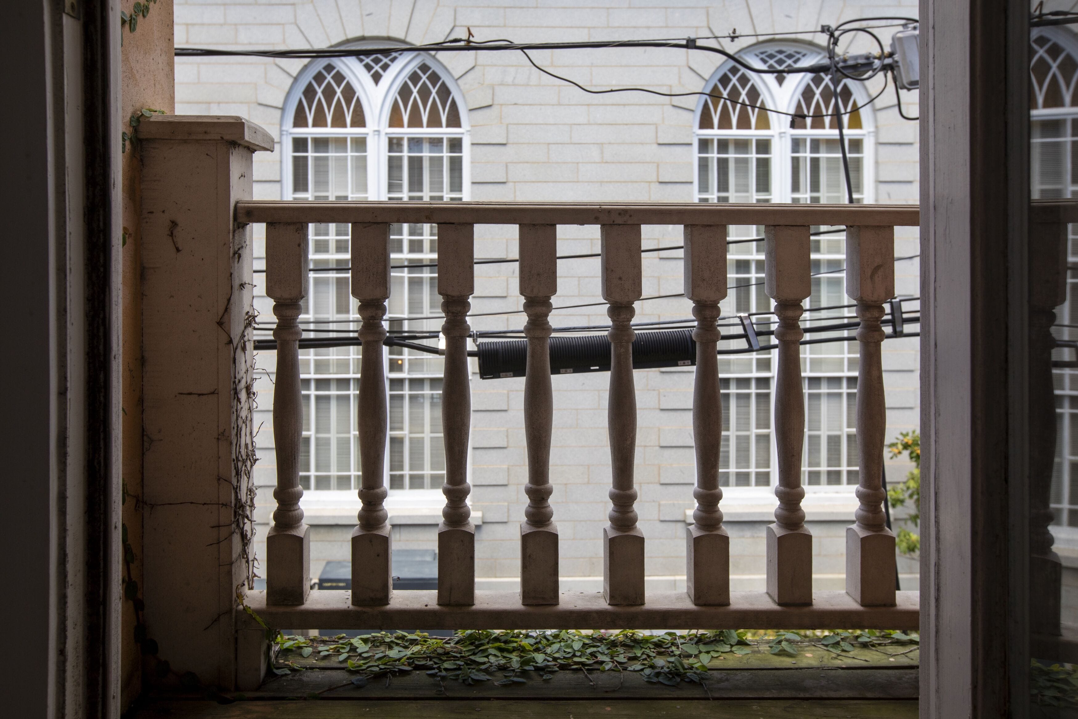 A wooden balcony railing with a view of a building with arched windows.