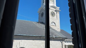A view through a window of a building with a clock tower and arched windows. - Foley House Inn (Savannah)