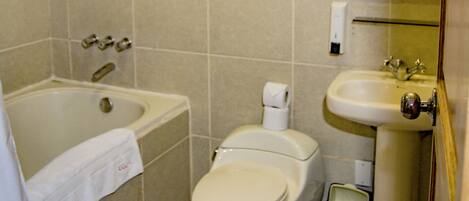 A standard bathroom with a bathtub, toilet, sink, and a mirror with a decorative frame.