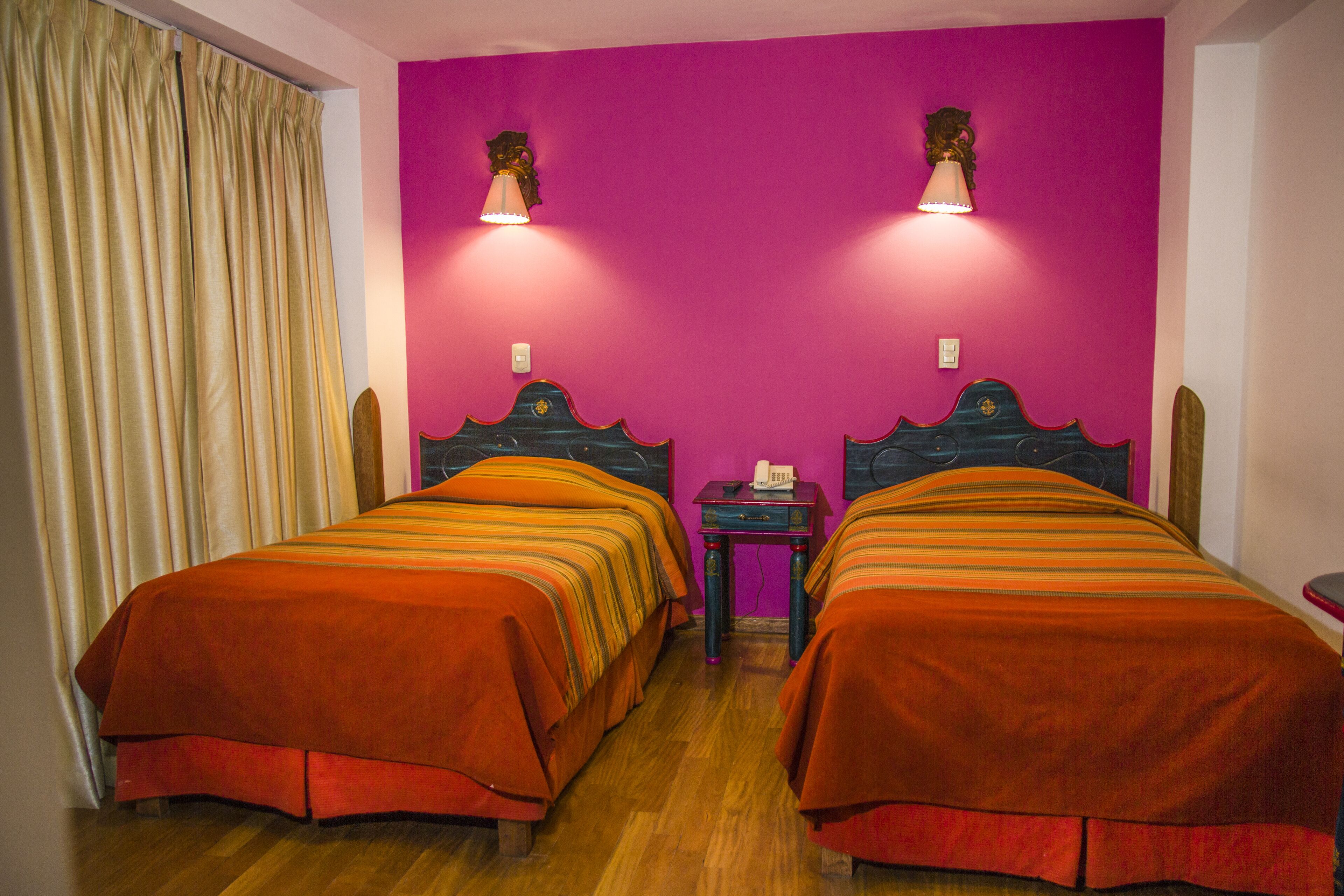 Ein Zimmer mit zwei Betten, einem kleinen Tisch und einer Wandlampe.