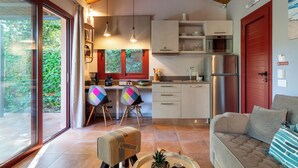 Una cocina moderna con un refrigerador de acero inoxidable, armarios de madera y una puerta roja. Hay un comedor con dos sillas y una mesa.