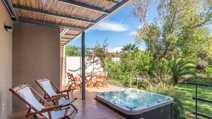 Un espacio exterior techado con un jacuzzi, sillones de descanso y una mesa de patio.