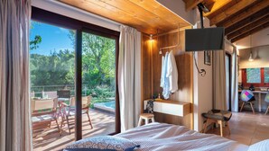 Un dormitorio con una cama grande, un televisor montado en la pared, un escritorio y vistas al exterior.