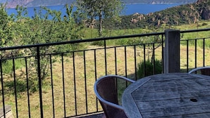 A balcony with a table and chairs, overlooking a mountainous landscape and a body of water. - Résidence de la Tour (Piana)
