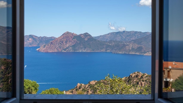 A view from a window overlooking a body of water with mountains in the background. - Résidence de la Tour (Piana)